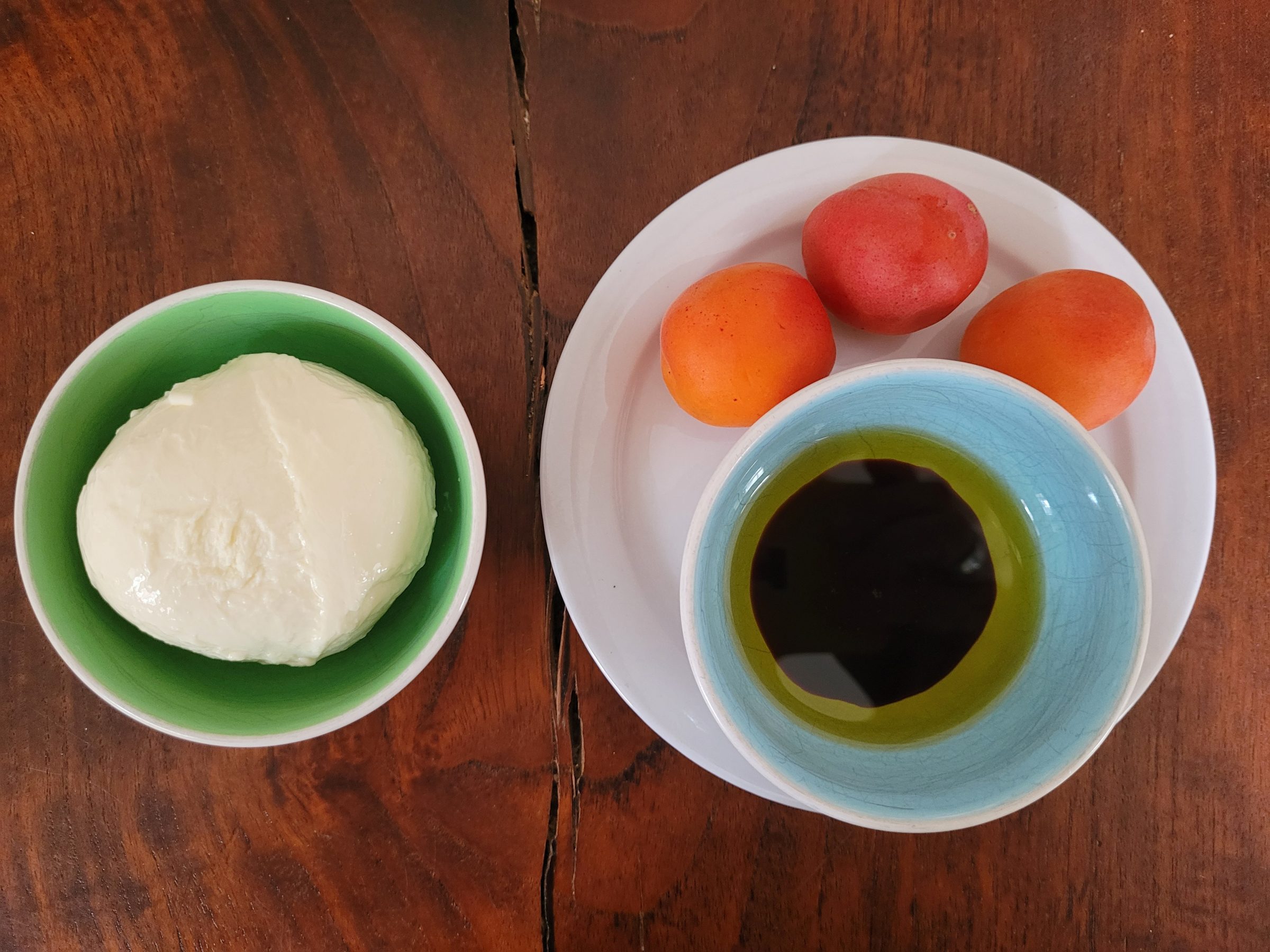 Mozzarella mit Aprikosen, Olivenoel und Aceto Balsamico arrangiert auf Holztisch